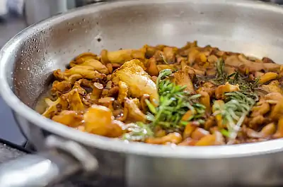 Buchen Sie einen Kochkurs in der Eventlocation Gaumenarche in Potsdam! Eine silberne Pfanne mit Pfifferlingen und Rosmarin bruzelt vor sich hin und duftet köstlich!
